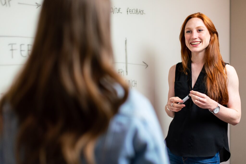 Woman in black sleeved top standing by a white board