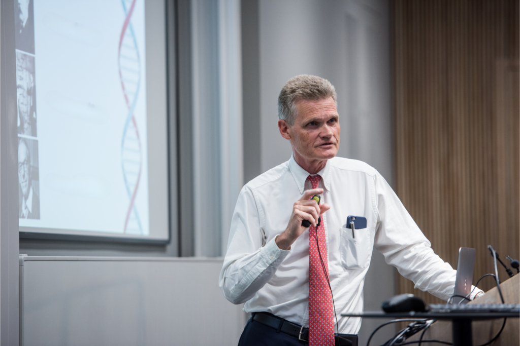 Professor Sir John Bell speaks at a conference.