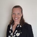 Photo of Harriet Teare,smiling, dressed in a black jacket with a flowery blouse.