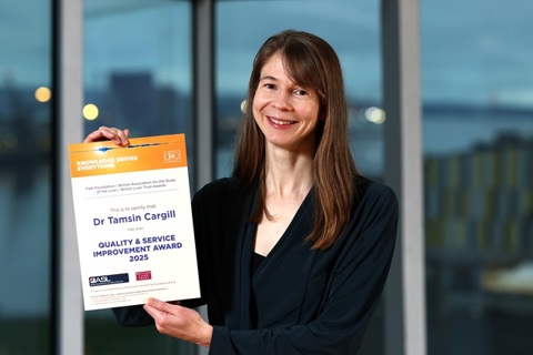 A lady with long brown hair holds a certificate.