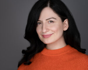 A lady with brown hair in an orange jumper