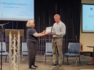 A man is given an award by a woman on stage