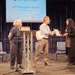 A lady receives an award at a lectern.