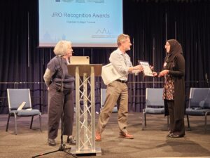 A lady receives an award at a lectern.
